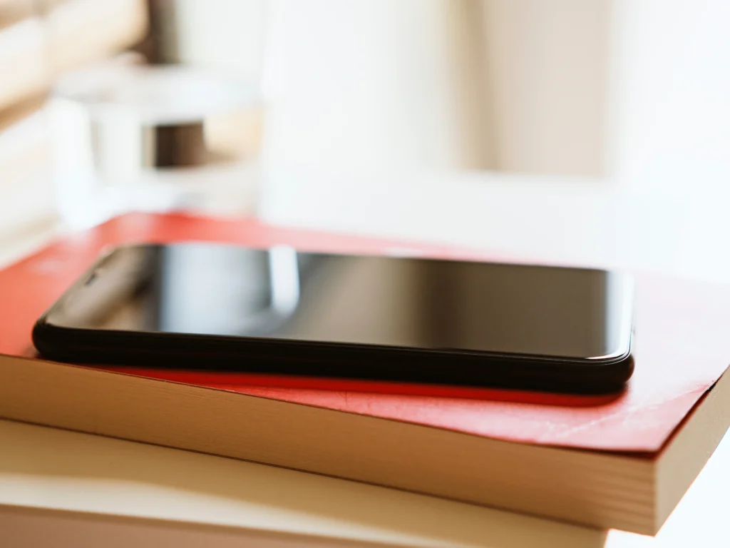 Telefon leżący na książkach symbolizujący świadomy wybór treści i informacji