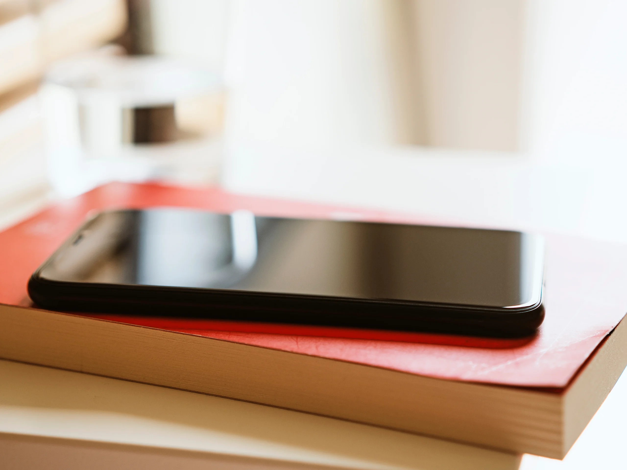 Telefon leżący na książkach symbolizujący świadomy wybór treści i informacji
